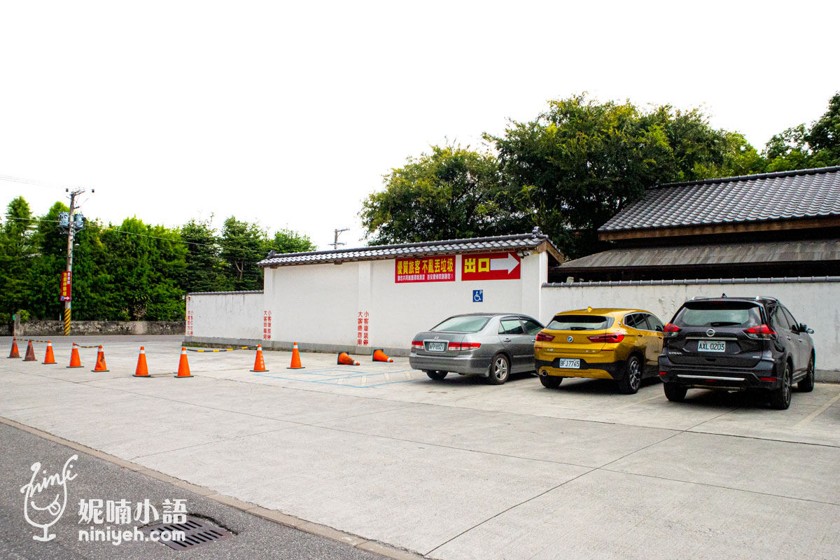 吉安慶修院寬敞的戶外水泥地停車場，後方為白色日式黑瓦外牆與出口指示標誌