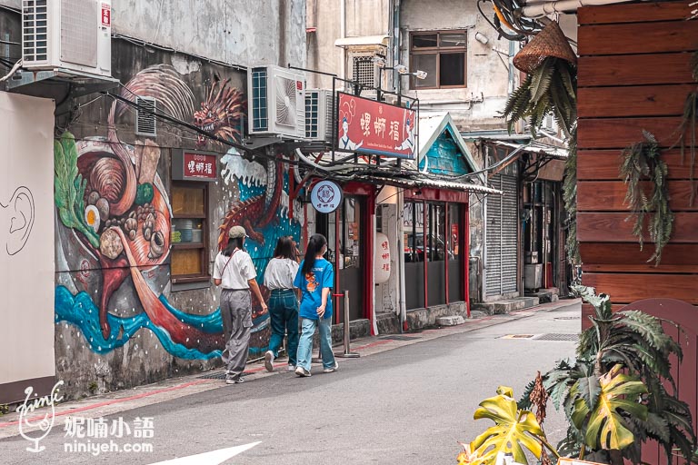 螺螄福餐廳的外部環境，三位顧客正從餐廳前經過，牆面上色彩鮮豔的螺螄粉主題塗鴉以及醒目的紅色招牌展現出濃厚的品牌特色。這張照片捕捉到餐廳所在街道的悠閒氛圍，將螺螄福打造成為赤峰街上一處引人注目的美食地標。