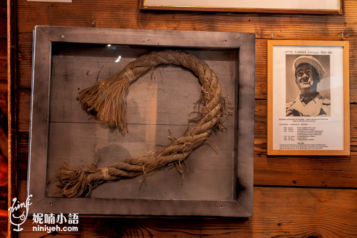 這張圖片展示了馬特洪峰博物館內的一段歷史登山繩，該繩子與1865年馬特洪峰首次登頂的山難有關，象徵著當時登山活動的危險性與挑戰。旁邊展示了一位策馬特著名的登山嚮導奧托·弗勒爾（Otto Furrer）的照片與簡介，這些展品強調了馬特洪峰在策馬特登山史上的重要地位，讓參觀者更加了解這座山峰的歷史和策馬特作為登山景點的意義。