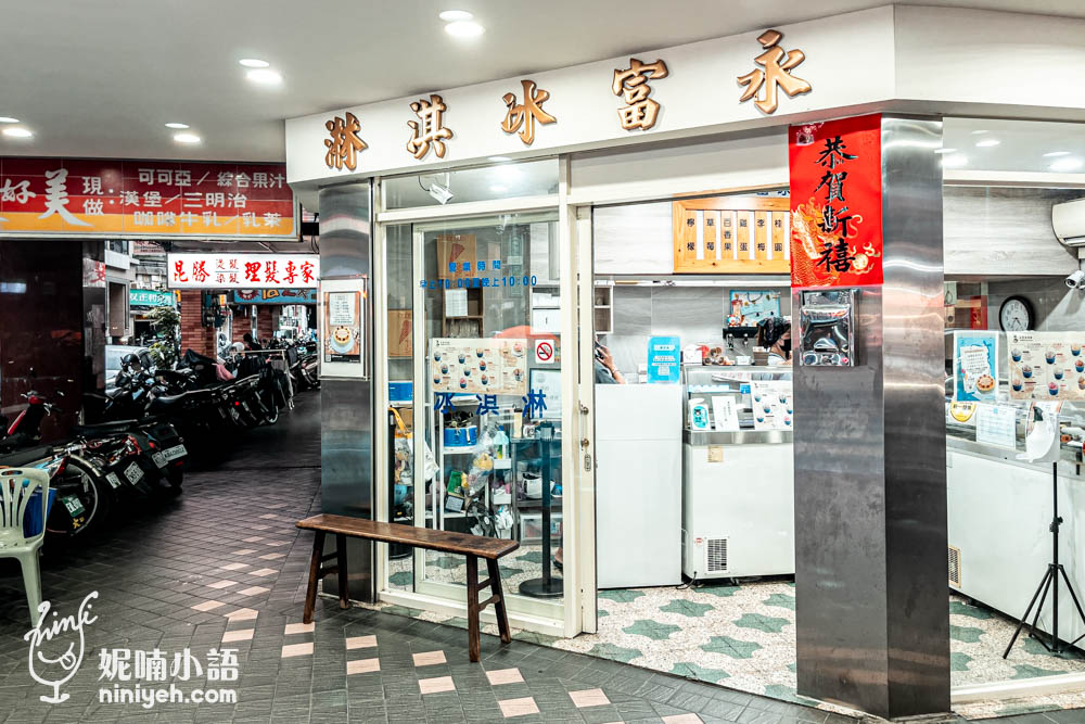 永富冰淇淋店面的外觀。雖然店面不大，但明亮的玻璃門和乾淨整潔的外觀給人親切的感覺。門口設置了簡單的木製板凳，方便顧客稍作休息或等待冰品，整體環境非常友好。招牌上以傳統字體寫著「永富冰淇淋」，彰顯出這家店的歷史與傳統魅力，吸引了不少在地居民與遊客前來品嚐這裡的古早味冰品。