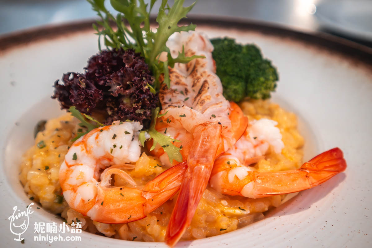 多燒蝦蟹黃燉飯,盤中盛滿金黃濃郁的蟹黃燉飯,上方擺放天使紅蝦、白蝦與燒烤干貝,搭配花椰菜與生菜點綴,色彩鮮明誘人。