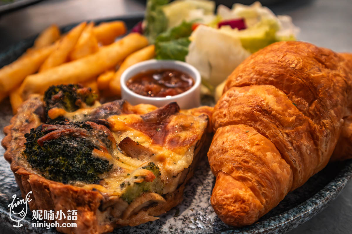 特寫拍攝禾多餐酒館季節鹹派早午餐,前景為酥脆可頌與西蘭花野菇鹹派,搭配小碟醬料,背景有炸薯條與蔬菜沙拉,色澤誘人。