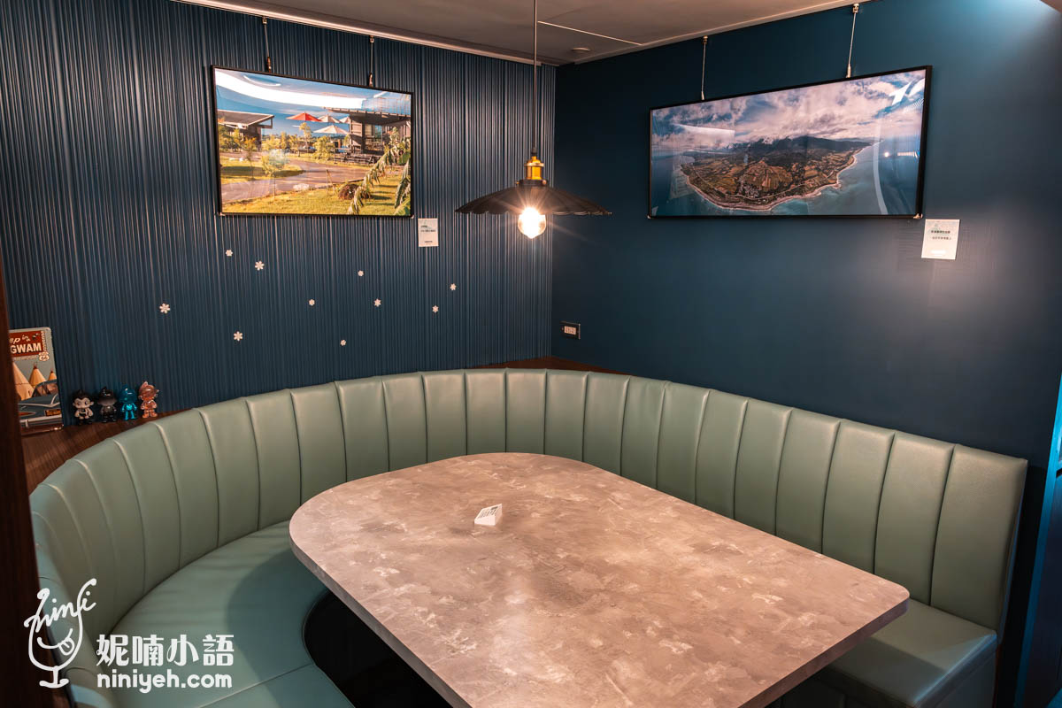 禾多餐酒館包廂式座位區,莫蘭迪綠色條紋軟質沙發環繞木質長桌,牆面掛有台東海景與農場風光照片,氛圍安靜舒適,適合多人聚餐或悠閒聊天。