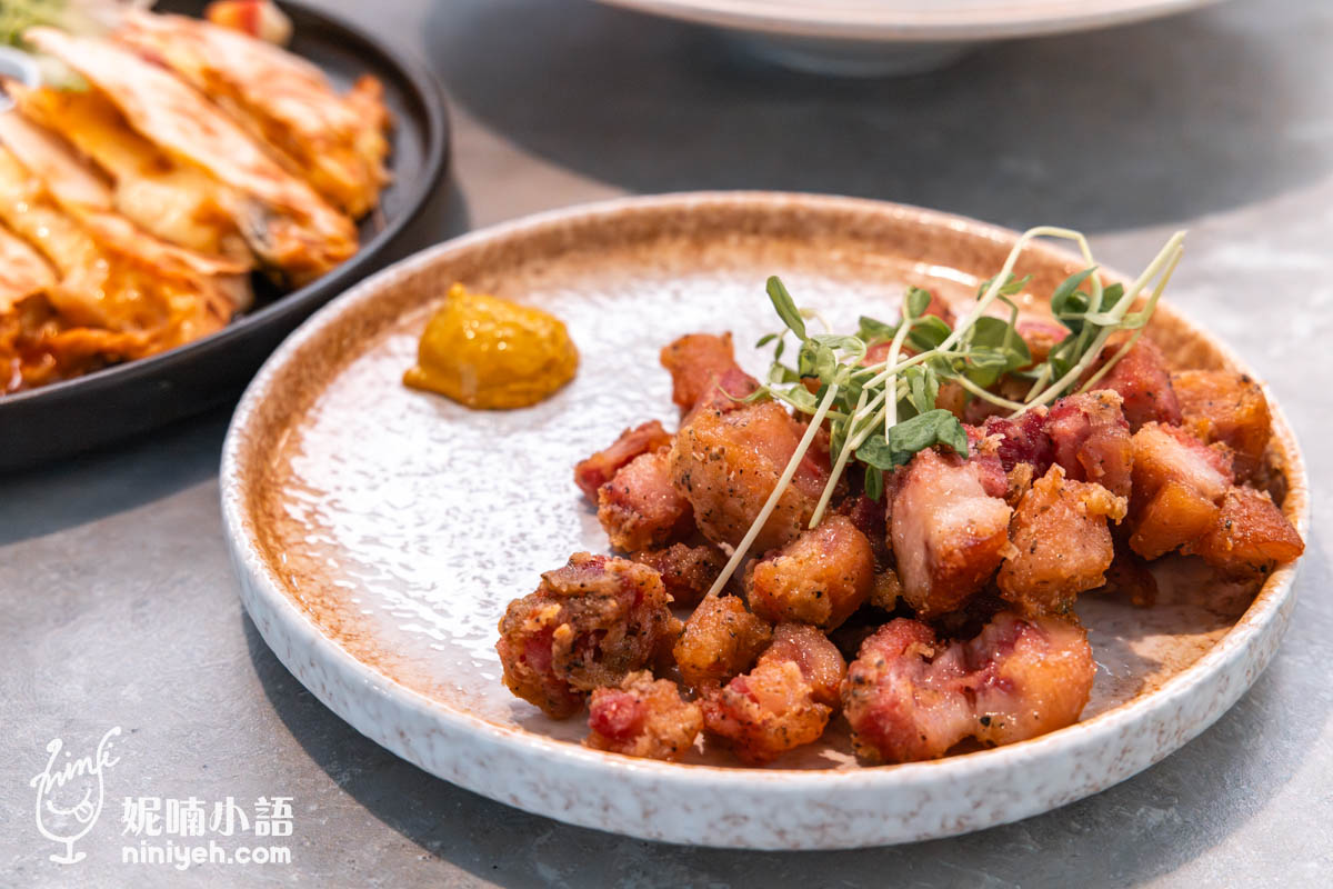 禾多餐酒館酥炸德國豬腳佐黃芥末,金黃酥脆的小塊豬腳擺放在陶瓷圓盤中,搭配黃芥末醬與綠色芽菜點綴,外酥內嫩。