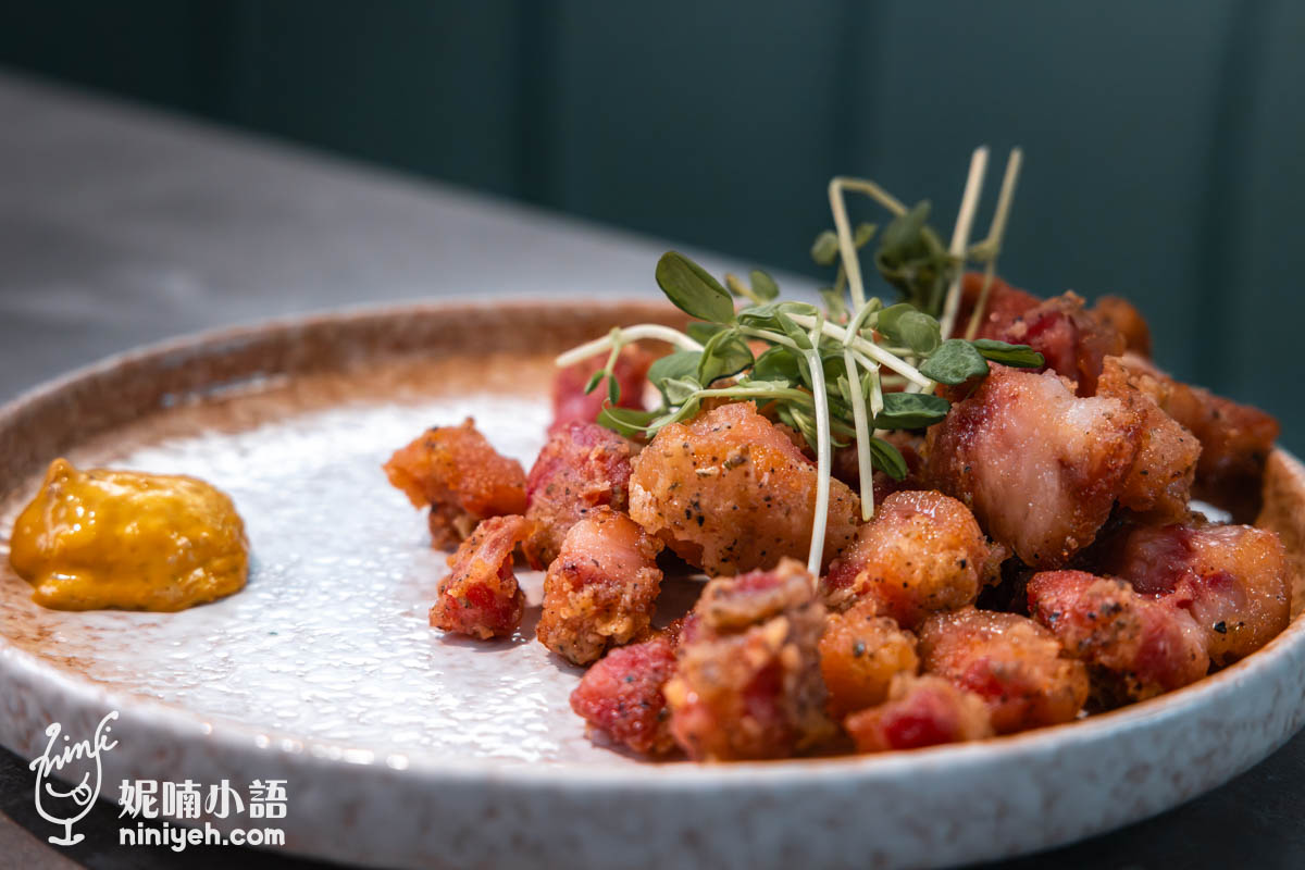 特寫拍攝酥炸德國豬腳佐黃芥末,金黃酥脆的豬腳塊搭配綠色芽菜擺盤,旁邊放有一小團黃芥末醬,外觀香脆可口。