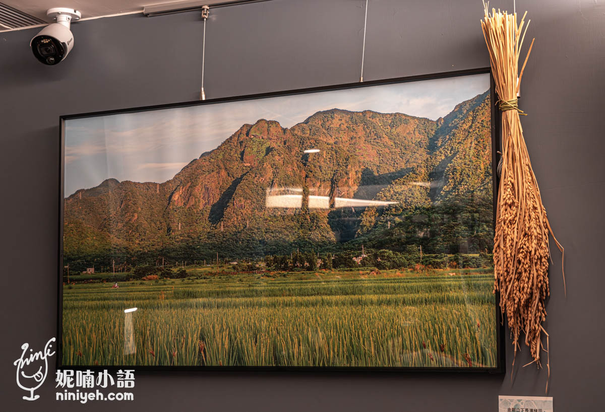 禾多餐酒館牆面掛著一幅金剛山與稻田風景照片，畫面前景是綠油油的水稻，右側裝飾有一束曬乾的稻穗，呈現濃厚的田園氛圍。