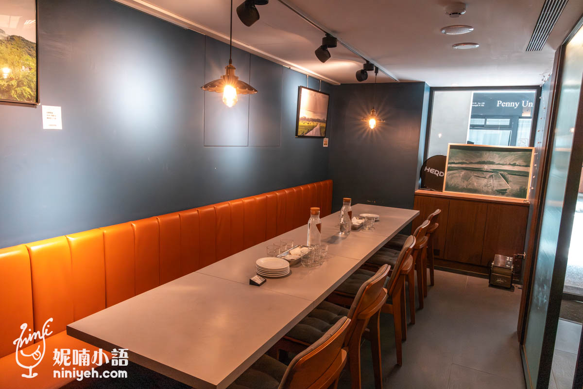 禾多餐酒館小巨蛋店獨立包廂,長桌搭配橙色皮質長椅與木質餐椅,可容納約10至12人,牆上掛有裝飾畫作,空間私密且適合多人聚餐。
