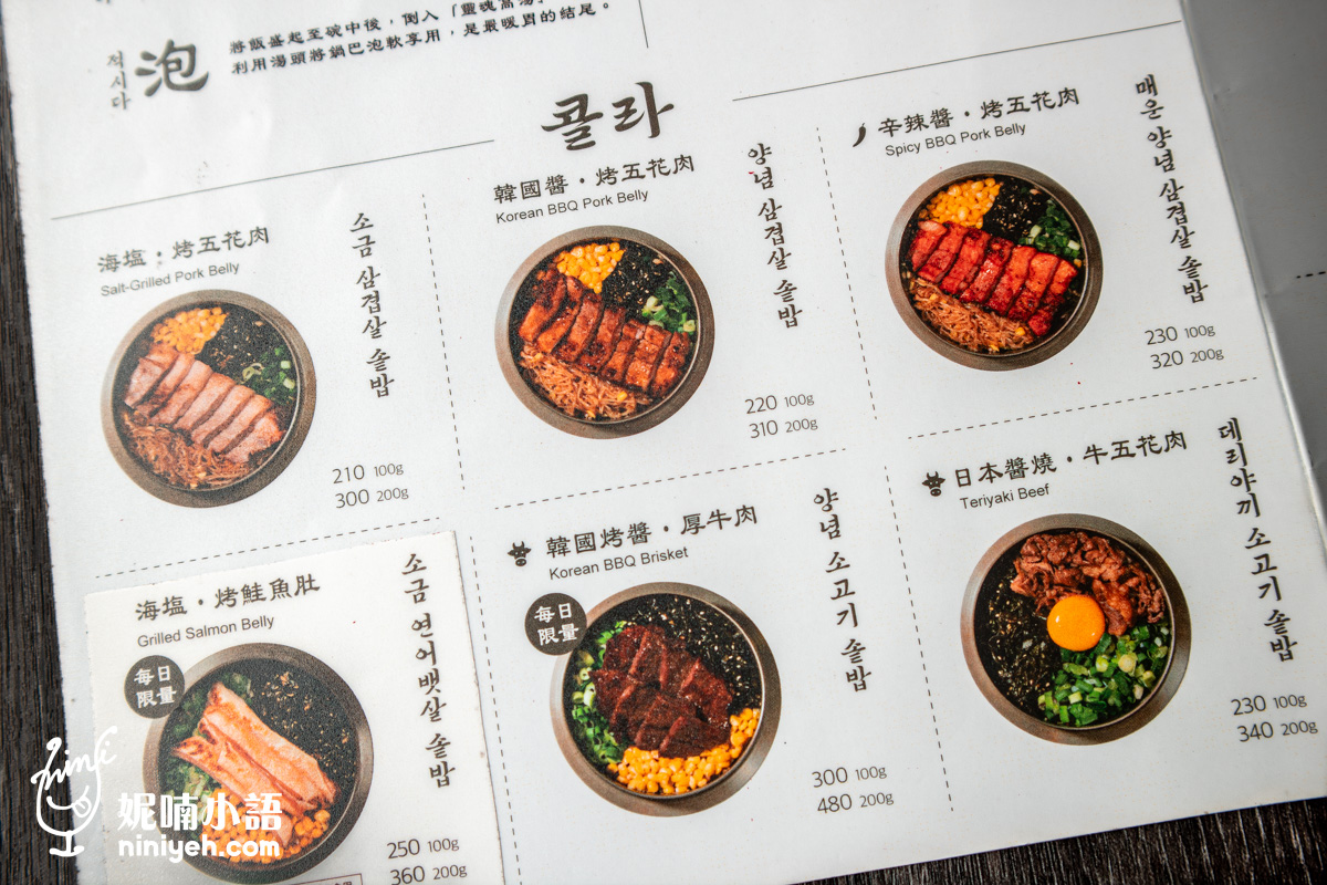 「金美麗人」韓式釜飯菜單的特寫鏡頭,清晰展示海鹽烤五花肉、韓國醬烤豬五花、辛辣醬烤豬五花、海鹽烤鮭魚肚、韓國烤醬厚牛肉以及日本醬燒牛五花的彩色圖片與 100g 或 200g 的肉量價格。