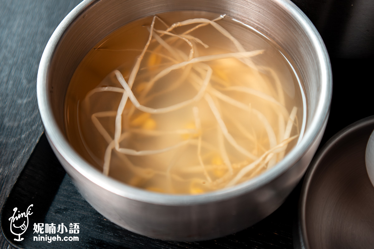 「金美麗人」釜飯定食隨餐附贈的靈魂湯品「豆芽高湯」,湯頭清澈並盛裝在雙層保溫不鏽鋼碗中。
