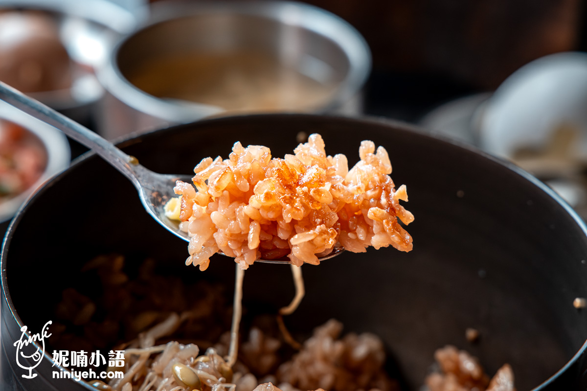 用湯匙舀起「金美麗人」韓式釜飯底部的金黃色鍋巴飯特寫,熱度收乾水分後呈現硬脆香濃的經典口感。