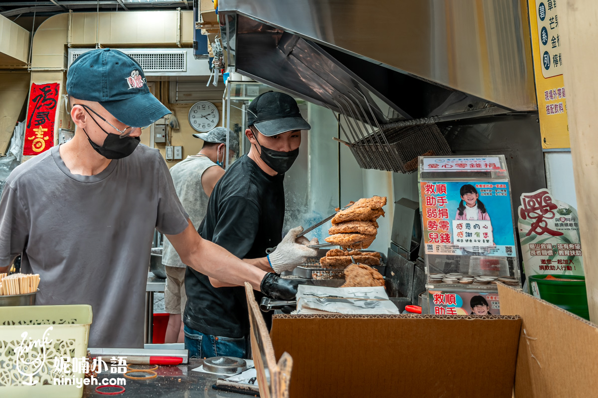 台北最強炸物推薦：緯大雞排大火現炸出爐實況。店員戴著手套，正熟練地將炸得金黃酥脆、厚實巨大的雞排從油鍋夾起送往前台包裝。