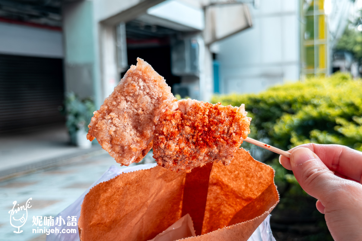 台北小巨蛋美食緯大雞排辣味特寫。竹籤串起的厚實炸雞塊，一半呈現傳統乾粉炸出的金黃顆粒感酥脆麵衣，另一半撒滿誘人的特製辣粉，剛從紙袋拿出的街頭小吃令人食指大動。