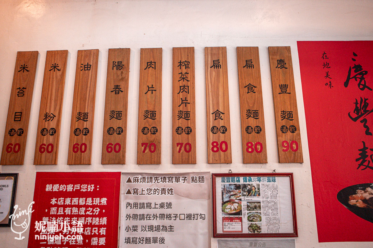 慶豐麵店牆上的木製菜單看板,清楚標示慶豐麵、扁食麵等麵食價格,下方附有內用外帶點餐說明的公告。